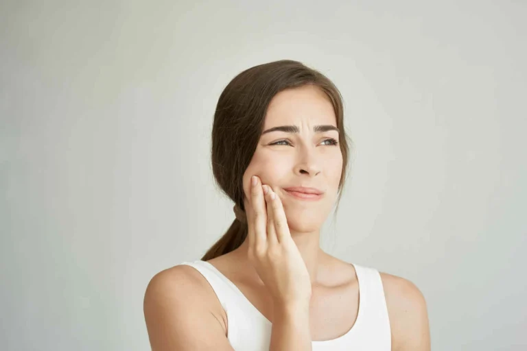 Woman holds hand on face teeth pain